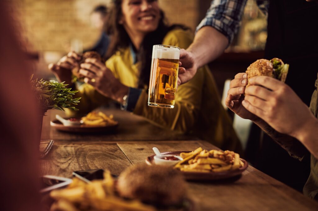 Close-up of waiter serving beer to guests who are eating in pub.